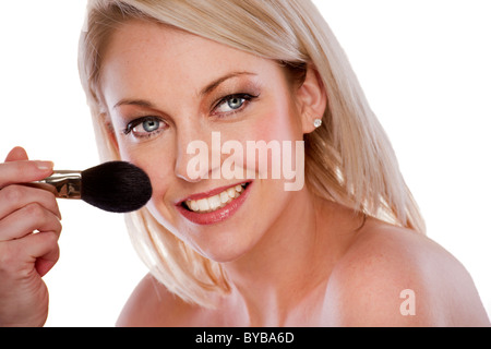 blonde woman applying powder with a brush Stock Photo