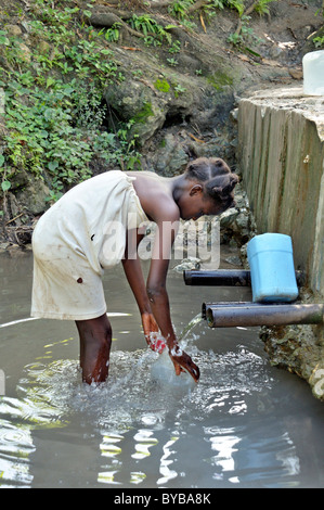Girl filling drinking water from a water source, Petit Goave, Haiti, Caribbean, Central America