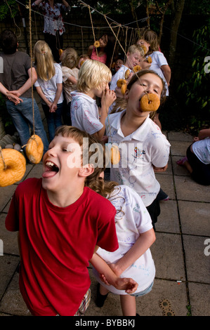 Children eating doughnuts off a string Stock Photo