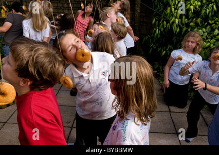 Children eating doughnuts off a string Stock Photo