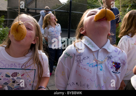 Children eating doughnuts off a string Stock Photo