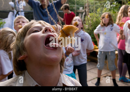 Children eating doughnuts off a string Stock Photo