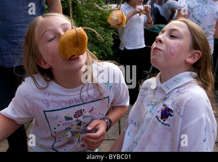 Children eating doughnuts off a string Stock Photo