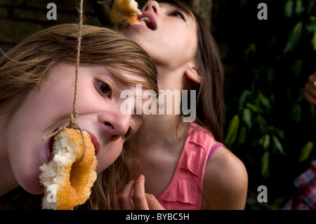 Children eating doughnuts off a string Stock Photo