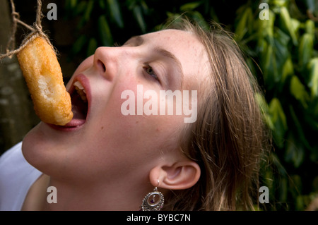 Child eating doughnuts off a string Stock Photo