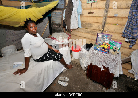 Pregnant woman, 15 years, sitting on her bed, village L'Acul near Leogane, Haiti, Caribbean, Central America Stock Photo