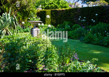 A small lawn in an English country garden in summer with a stone planter on a plinth. Cropped version available BYBFRY Stock Photo