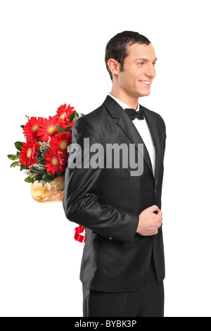 Man wearing suit and bow tie hiding a bouquet of flowers behind his back Stock Photo