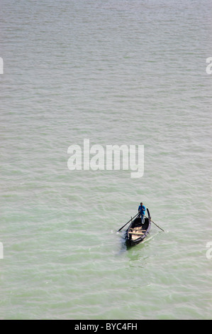 A solitary Bangladeshi man rowing wooden boat down river in Daka, capital of Bangladesh Stock Photo