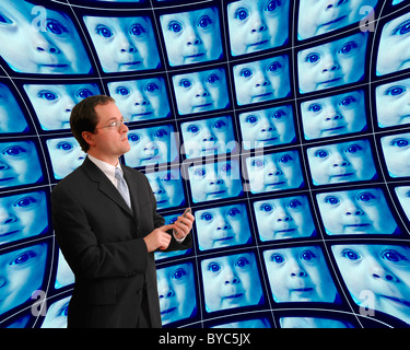 Man in suit monitoring babies on distorted bluish video screens Stock Photo