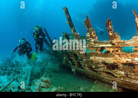 Group of scuba divers on wooden wreeckship. Divers inspects the skeleton of a wooden vessel Stock Photo