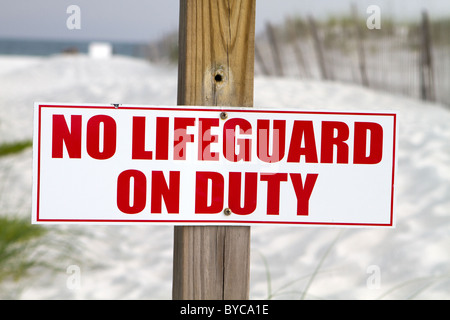 Sign posted at a beach notifies swimmers that there is no lifeguard on duty. Stock Photo