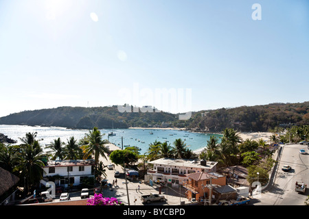 view down on town pier main street palm fringed beaches & sparkling  harbor with anchored boats Puerto Angel Oaxaca State Mexico Stock Photo