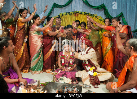 Guests throw rice grains over a newly married couple to symbolize abundance and good fortune at a Hindu wedding in India Stock Photo