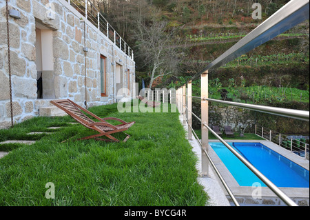 Terrace with wooden lounge chair on lawn over a swimming pool at the Casas da Lapa hotel, Lapa dos Dinheiros, Portugal Stock Photo