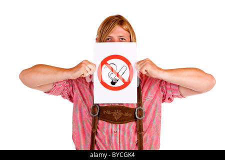 Bavarian man in lederhose holds no-smoking-rule sign in front of face. Isolated on white background. Stock Photo