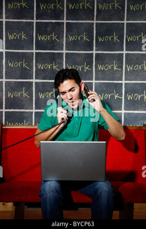 Frustrated office worker overworked workaholic talking on phone and working on laptop. Stock Photo