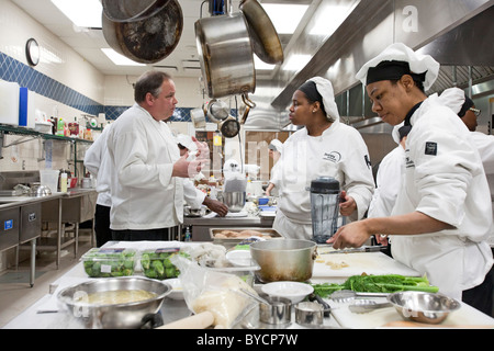 Instructor John Adamski works with students preparing food at the Dorsey Culinary Academy, a private career training school. Stock Photo