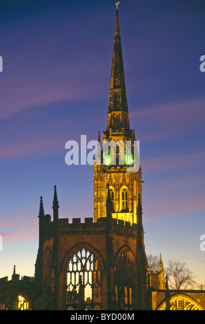 Old St Michaels floodlit historical Coventry cathedral tower & spire building with shell of bombed out ruins of nave at dusk West Midlands England UK Stock Photo