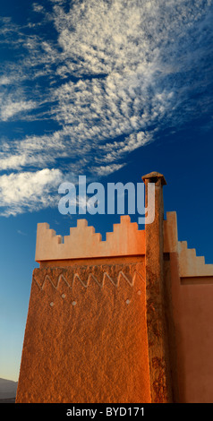 Texture and pattern of Berber pise architecture with chimney and puffy clouds at sunrise in Tinerhir Morocco Stock Photo