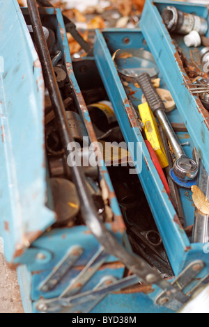 An old blue rusty metal tool box lying on the floor of a garage. Stock Photo