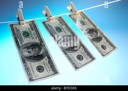 Hundred dollar bills drying on a clothes line isolated on blue sky background Money laundering concept Stock Photo