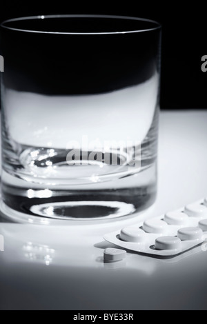 Tablets in a blister pack beside a glass of water Stock Photo