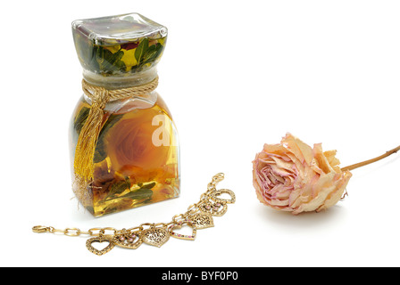 Bath oils, dried rose, and heart shaped bracelet isolated on white. Stock Photo