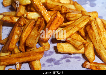 golden brown freshly cooked home made chips made from irish potatoes drying on ktichen paper Stock Photo