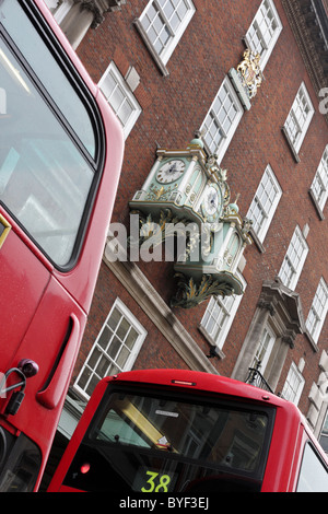 Extreme angled aspect of the famous Fortnum and Mason clock,viewed here between two of London`s buses in Piccadilly. Stock Photo