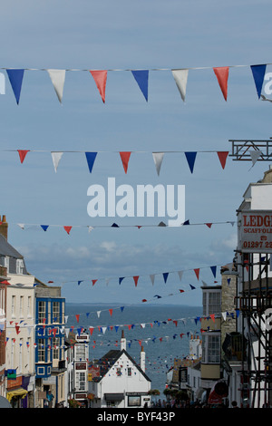 Bunting crosses the high street (Bridge Street) in Lyme Regis with the sea in the background Stock Photo