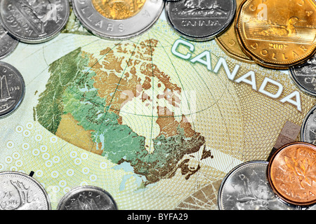 Close up of a one hundred canadian dollar bill showing the map of Canada, surrounded by loony and tuney coins. Stock Photo