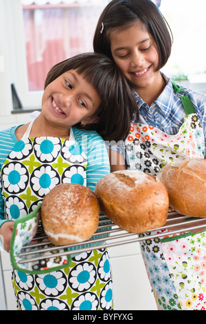 Two girls holding fresh bread in kitchen Stock Photo