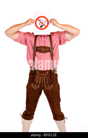 Bavarian man in lederhose holds no-smoking-rule sign in front of face. Isolated on white background. Stock Photo