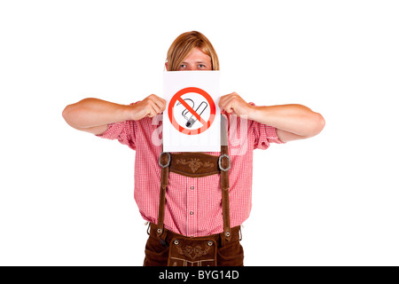 Bavarian man in lederhose holds no-smoking-rule sign in front of face. Isolated on white background. Stock Photo