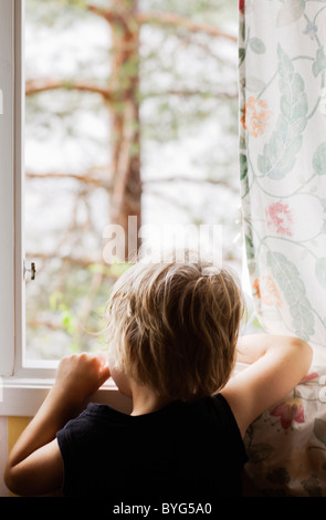 Boy looking through window Stock Photo