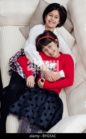 Two sisters lying on sofa, overhead view Stock Photo