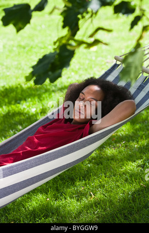 Young man with afro hair sleeping in hammock in park Stock Photo