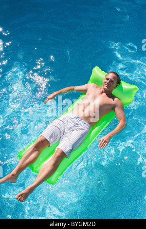 Man on inflatable raft in swimming pool Stock Photo