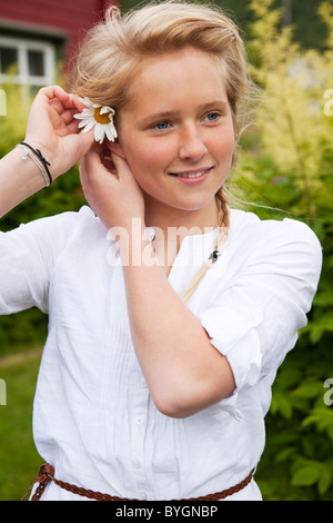 Portrait of teenage girl putting flower in hair