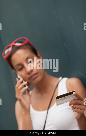 Woman using mobile phone holding credit card Stock Photo