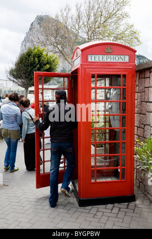Young man / tourist entering an original K6 red telephone / phone call box on Gibraltar, near border with Spain. Rock of Gibraltar. Stock Photo