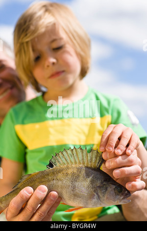 Father and son holding fish, focus on foreground Stock Photo