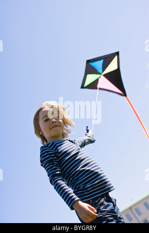 Portrait of boy  flying kite in bright sunlight, against clear sky Stock Photo