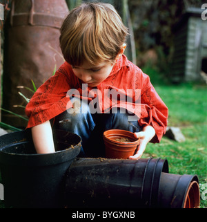 Child gardening young boy 4 filling plastic pots with soil to prepare for sowing seeds in a country garden in spring Carmarthenshire Wales UK  KATHY DEWITT Stock Photo