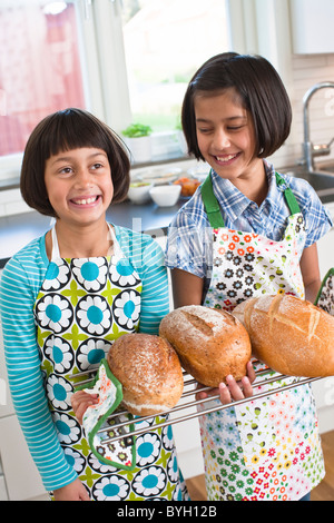 Two girls holding fresh bread in kitchen Stock Photo