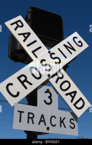 Railroad crossing sign with three tracks against a blue sky. Stock Photo