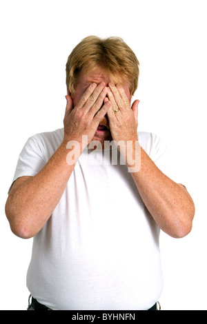 Man covers his eyes with his hands to shield himself from the sight. Stock Photo