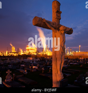 USA, Louisiana, Baton Rouge, Statue of Jesus Christ in Holy Rosary Cemetery near petrochemical plant at dusk on summer evening Stock Photo