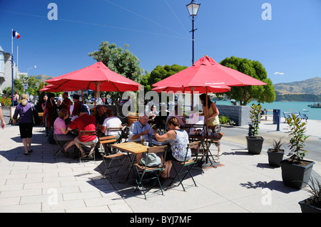 Tourists having lunch in the hot sun at one of the many outdoor eateries along Beach Road in the small picturesque historic town of Akaroa, Canterbury Stock Photo